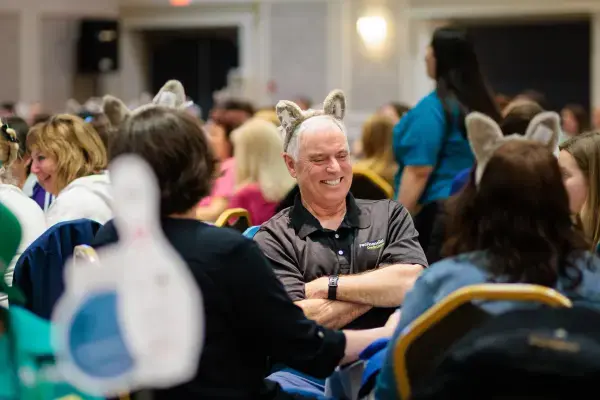 Older gentleman smiling and wearing wolf ears in a full ballroom
